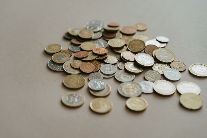 A collection of assorted coins scattered on a beige surface, related to overheard conversations.