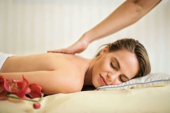Person enjoying a luxurious massage, a desired rich people activity, with flowers beside them on a soft pillow.