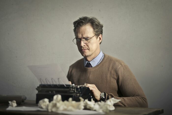 A person using a typewriter, with crumpled paper around, representing 2025-Trends in creative writing.