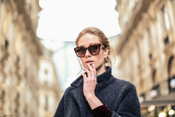 Stylish woman in sunglasses on a city street, exuding confidence, embodying the concept of self-paying-products.