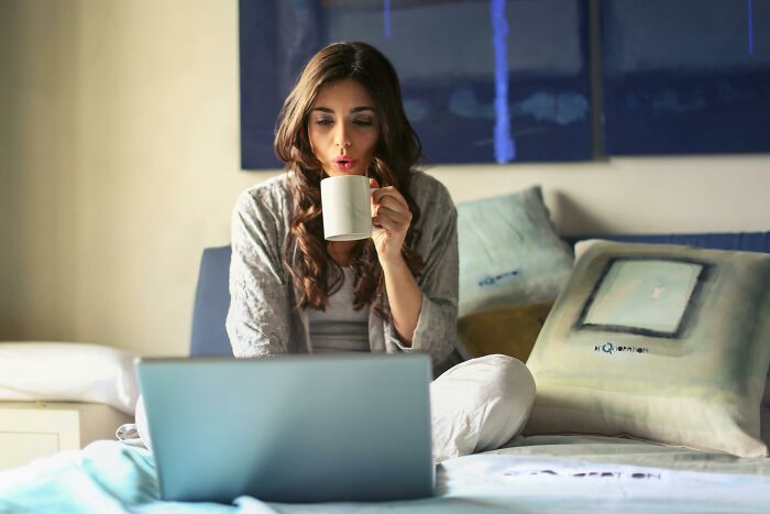 A woman enjoying coffee while using a laptop, representing the childfree lifestyle.