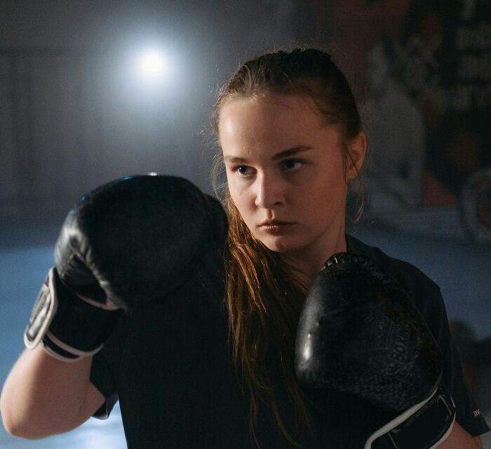Young woman boxing in a gym, showcasing her dedication and love for the sport.