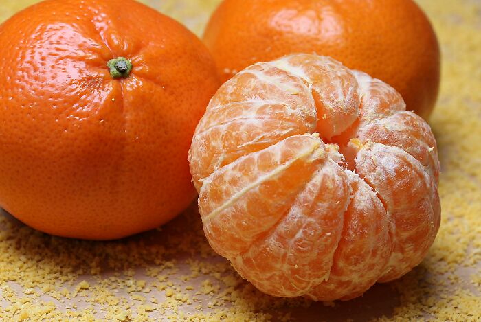 Two whole tangerines and one peeled, showcasing health-boosting fruits.