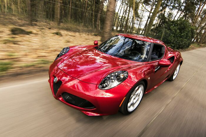 Red sports car driving on a forest road, illustrating future predictions aged bad in automotive design.