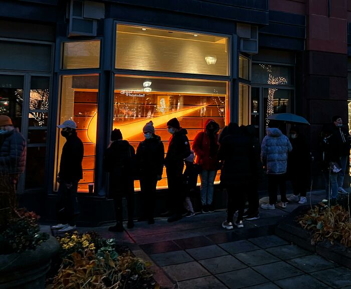 People waiting in line outside a store at night, illustrating bizarre things real men don’t do perceptions.