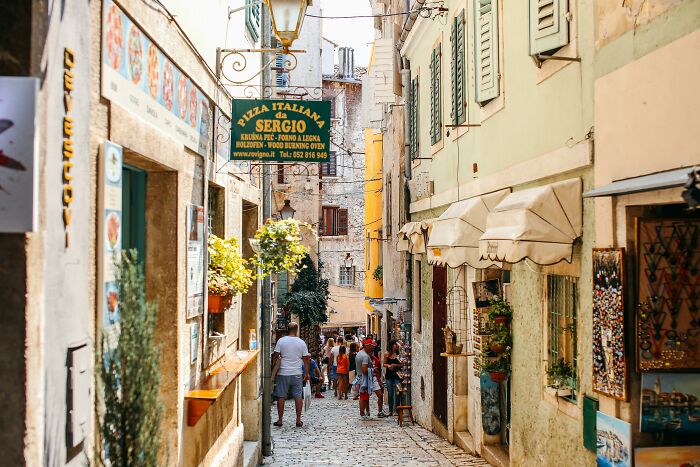 A narrow European street bustling with tourists, showcasing cultural differences in architecture and atmosphere.
