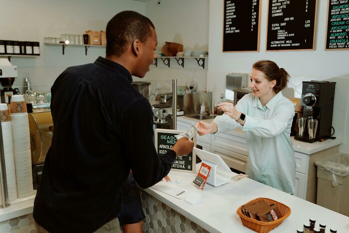 Customer paying barista at a coffee shop counter, exemplifying social rules people often ignore in daily interactions.
