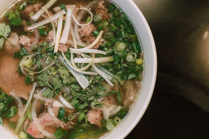 Bowl of pho with fresh herbs and spring onions, illustrating one of the best perks of not having to go to the office.
