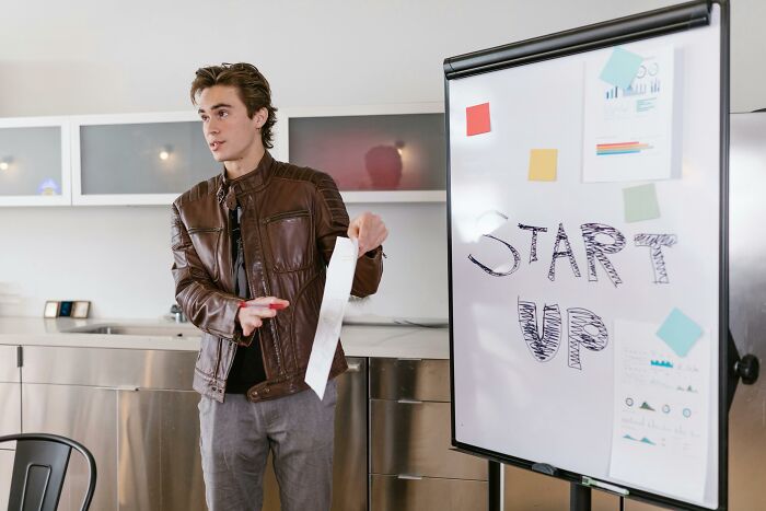 Person presenting startup ideas on a whiteboard, highlighting common work skills people lack in business settings.