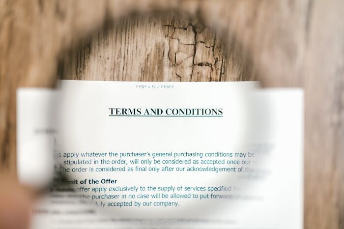 Magnifying glass over a "Terms and Conditions" document on a wooden table, symbolizing world facts and perspectives.