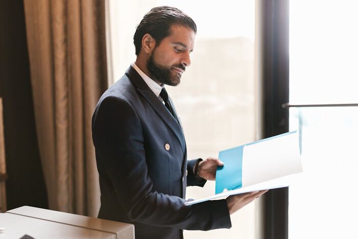 A man in a suit reads a document by a window, conceptually linked to "songs as ringtones."