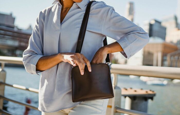 A person in a light blue shirt reaching into a brown bag, symbolizing expressions of love and care.
