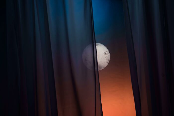 Moon peeking through curtains against a twilight sky, illustrating brilliant life hacks for capturing natural beauty.
