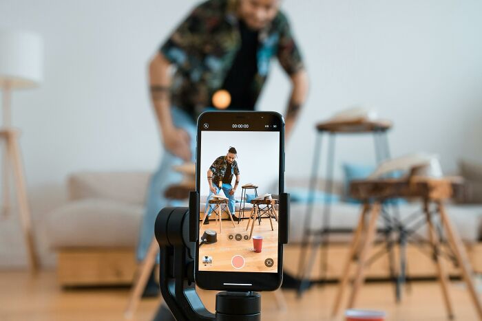 Person setting up a video shoot with a smartphone on a stand, capturing evolving 2025-Trends.