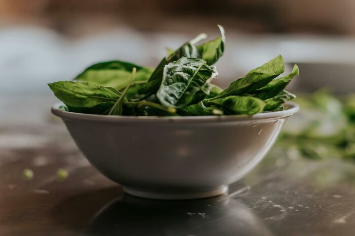 Bowl of fresh green leaves on a kitchen counter, illustrating parenting hacks for healthy eating.