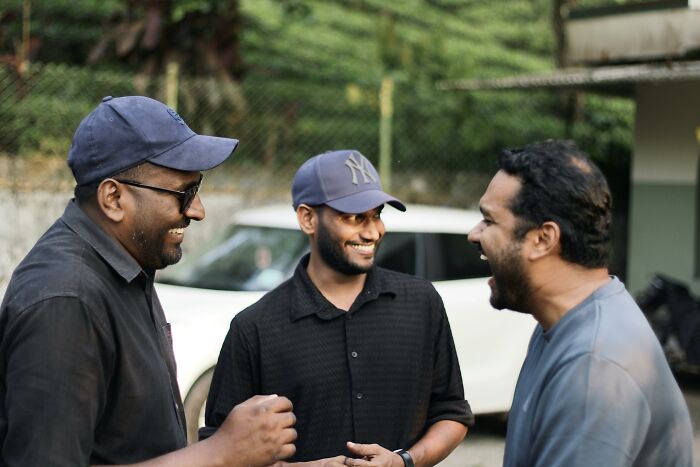 Three men laughing together, capturing a moment of hilarious overheard conversations outdoors.