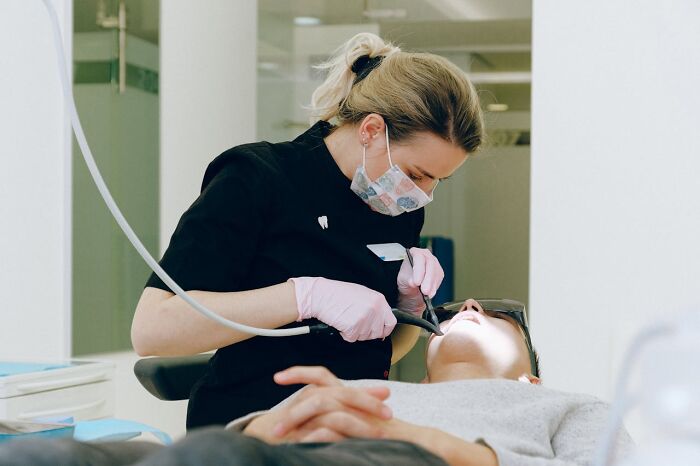 Dental professional working on a patient in a clinic, highlighting assumptions about people’s jobs.