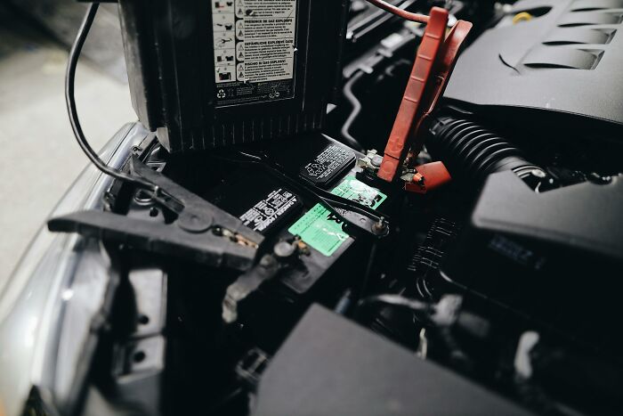 Car battery with jumper cables connected, illustrating self-paying-products in automotive maintenance.