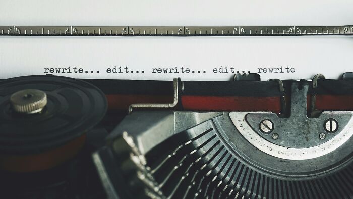 Close-up of a vintage typewriter typing the phrase rewrite edit, symbolizing things associated only with rich people.