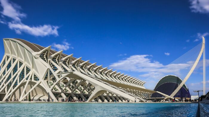 Futuristic architectural styles featuring sleek curves and geometric patterns under a clear blue sky.