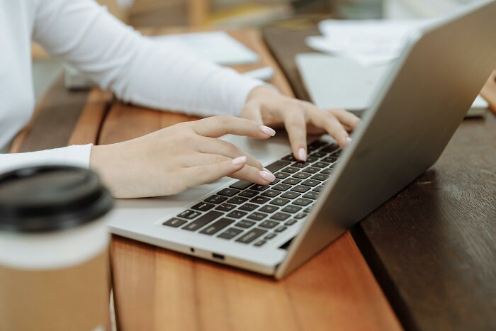 Person typing on a laptop at a wooden desk, highlighting work skills people lack in digital environments.