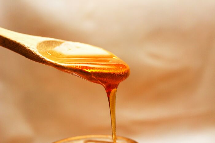 Honey dripping from a wooden spoon, showcasing a brilliant life hack for sweetening meals naturally.