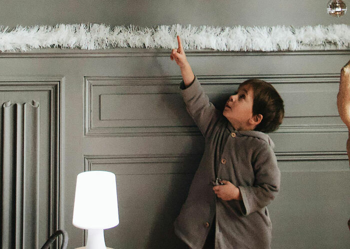 Child pointing upward in a dimly lit room, illustrating a creepy family moment.