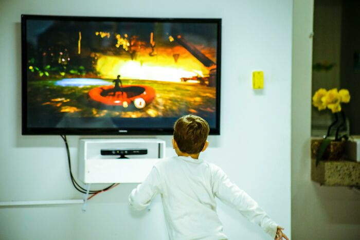 Child playing a video game on a TV, capturing an exciting mic-drop moment.