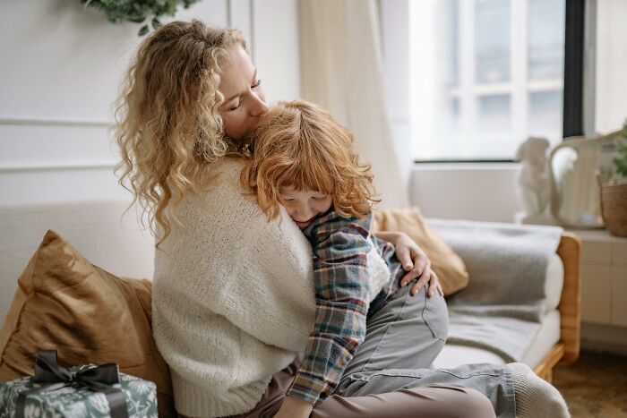 A person hugging a child in a cozy living room, showing love and affection.