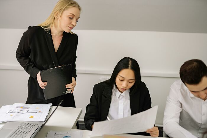 Colleagues in a meeting looking at documents, illustrating work-struggles in an office environment.