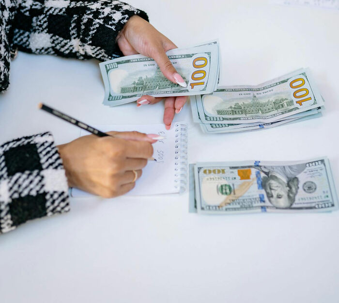 Person budgeting with dollars on table, representing frugal spending.