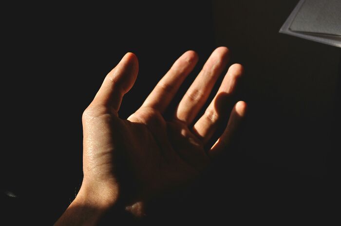 Hand in shadow, palm open, symbolizing the superstition about itchy palms and expecting money.