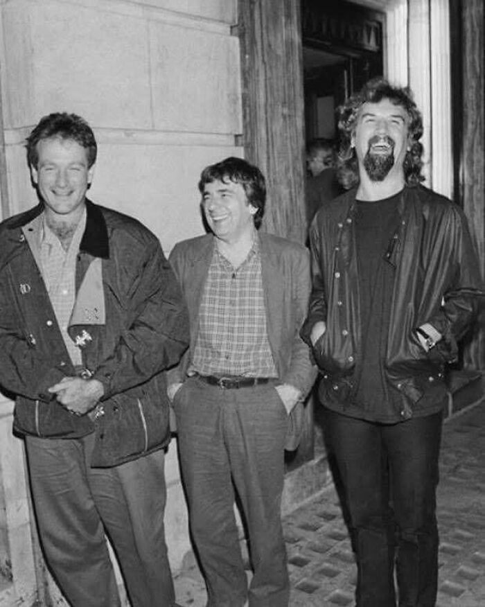 Three people laughing together outdoors, capturing a moment in history.