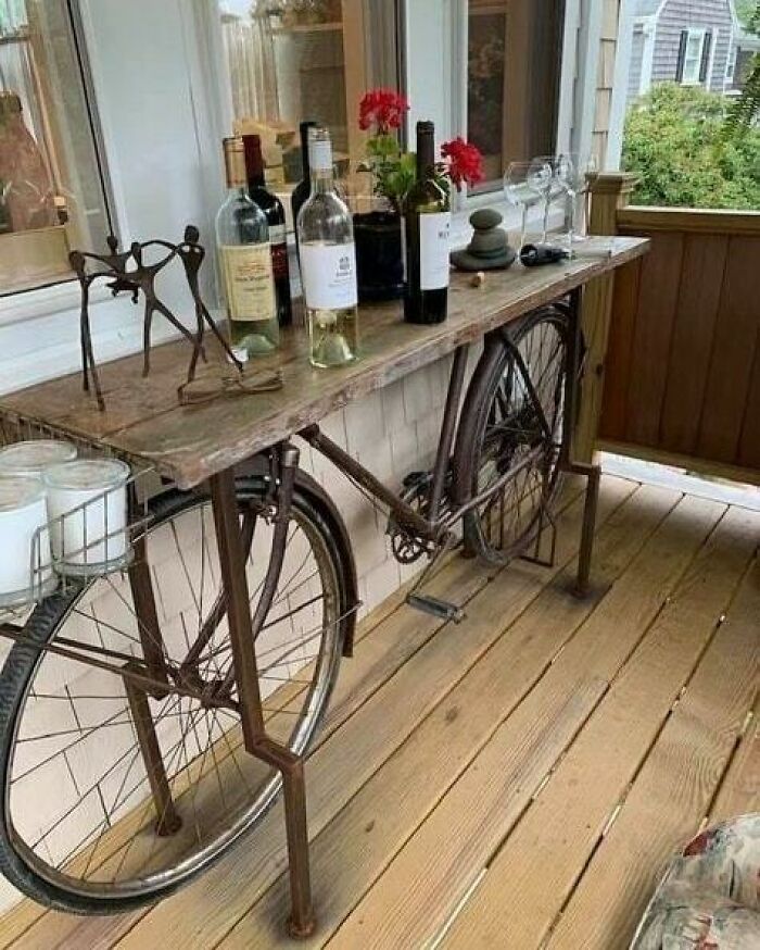 Recycled bicycle frame turned into a decorative table with wine bottles and glasses.