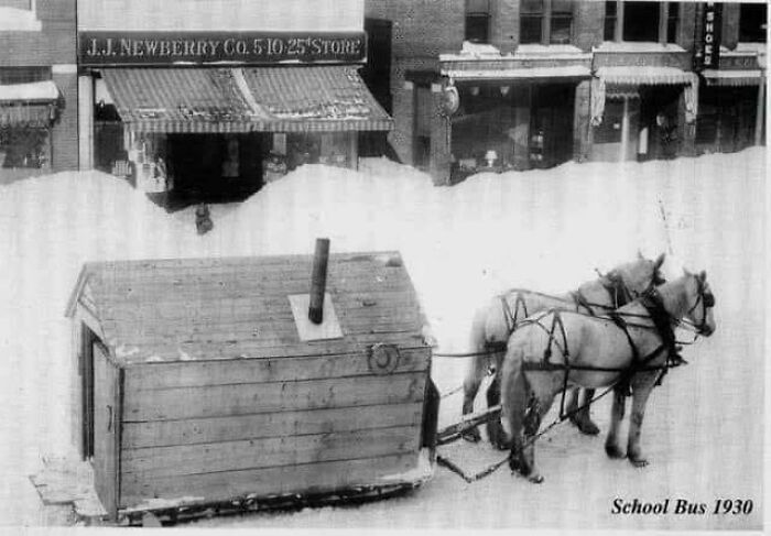 Horse-drawn school bus from 1930 outside a store, showcasing a piece of interesting history with snowy streets.