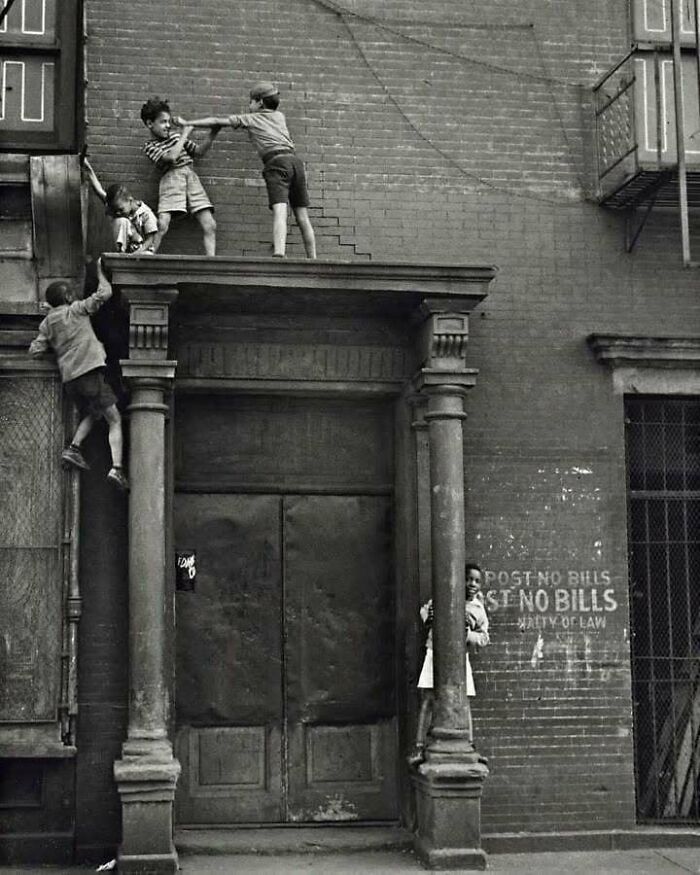 Children playing on a historic building's facade, showcasing something interesting from history.
