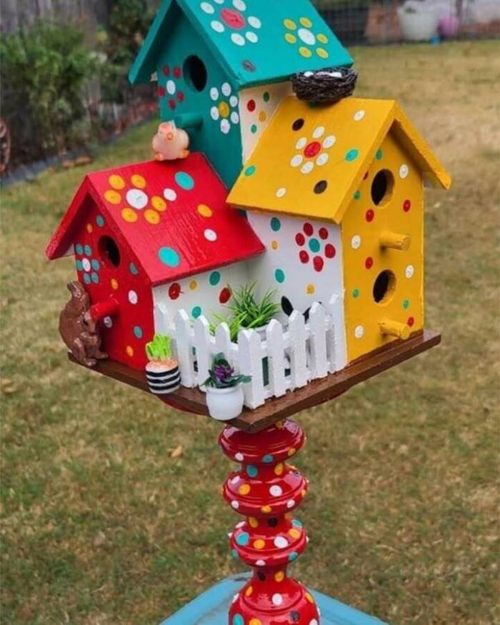 Colorful birdhouses repurposed from recycled materials with decorative polka dots in a garden setting.