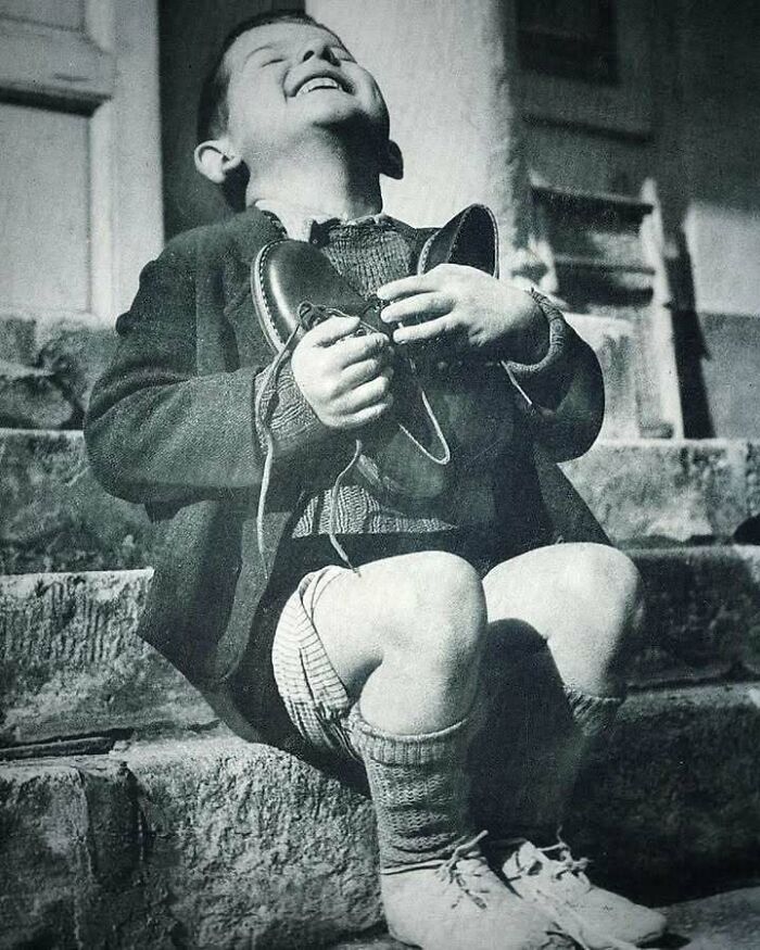 A joyful child clutching new shoes, representing an interesting moment in history.
