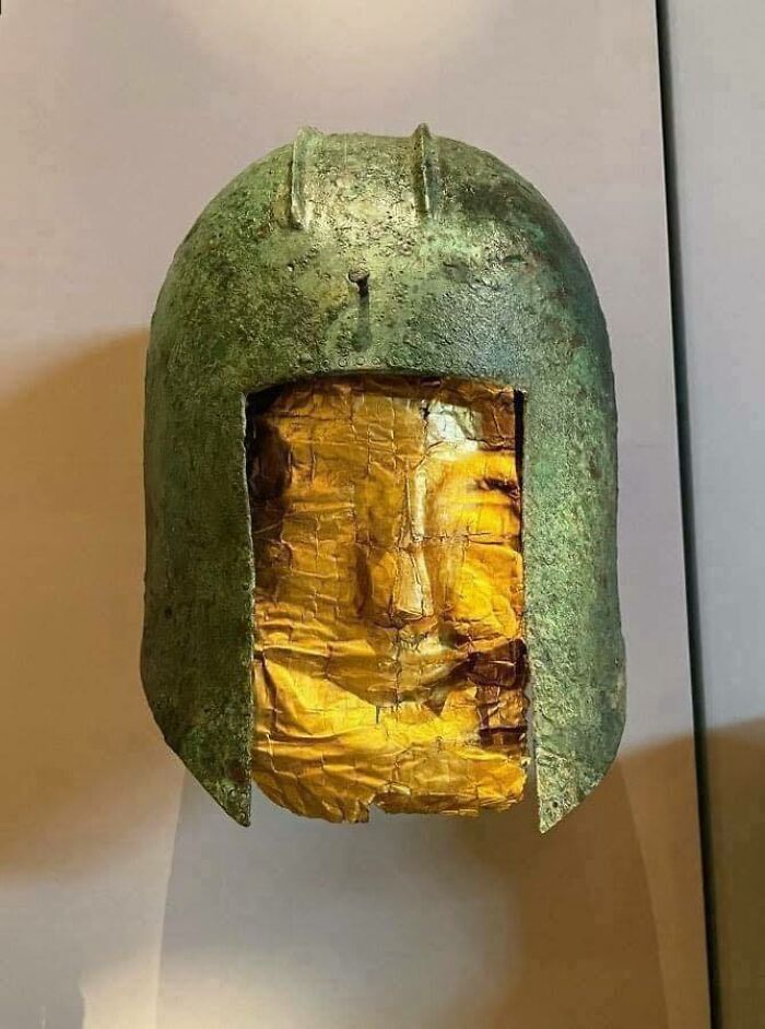 Ancient helmet with gold mask, an interesting historical artifact displayed in a museum setting.