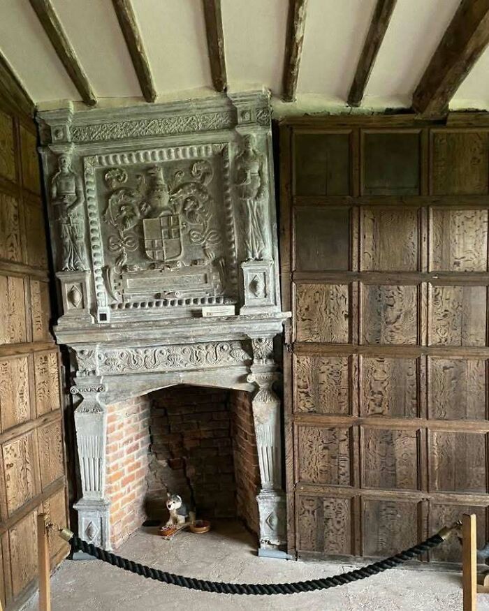 Historic ornate fireplace with intricate carvings, surrounded by wooden paneling.