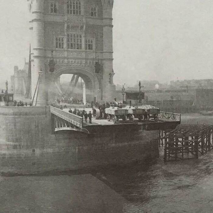Historic image of Tower Bridge under construction with workers and vehicles present.