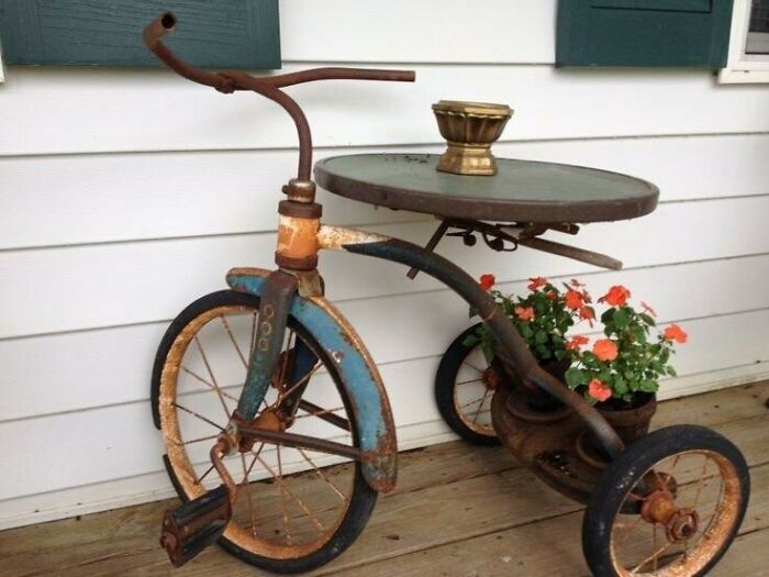 Recycled tricycle transformed into a unique outdoor table with flower pot.