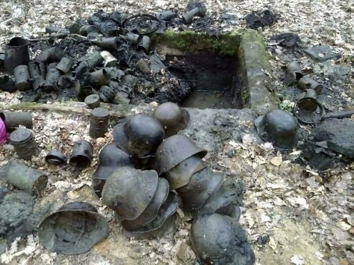 Historical artifacts including helmets and containers discovered in a forest clearing.