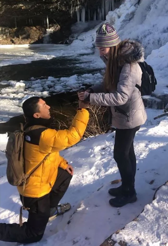 Man kneeling in the snow, proposing with a ring, as a woman smiles at a scenic icy backdrop. Photographs with terrifying backstories.