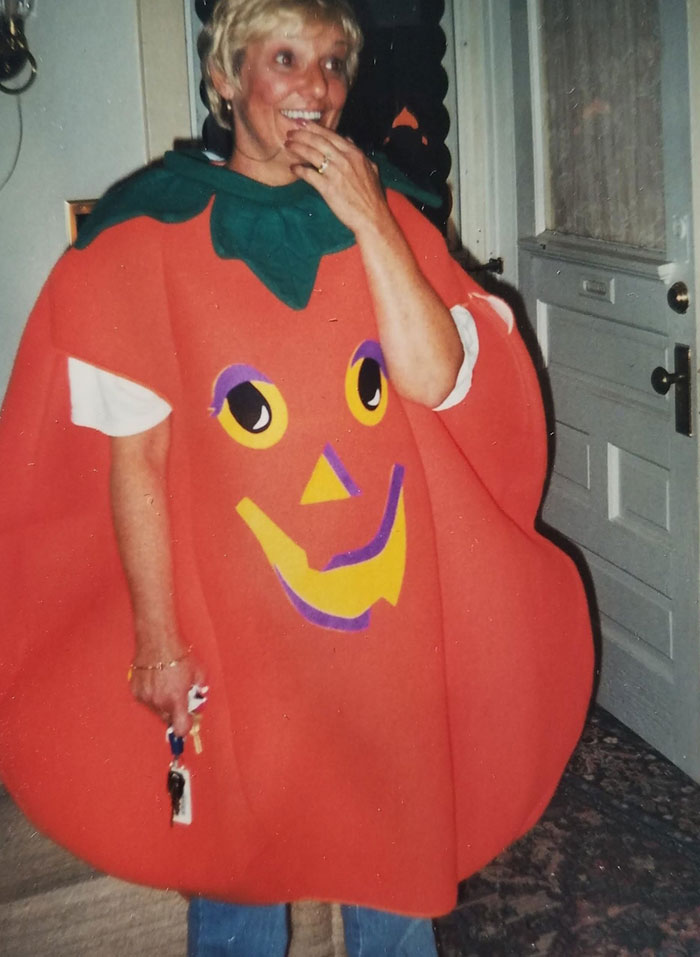 Person in a playful pumpkin costume, smiling inside a home, with a terrifying backstory.