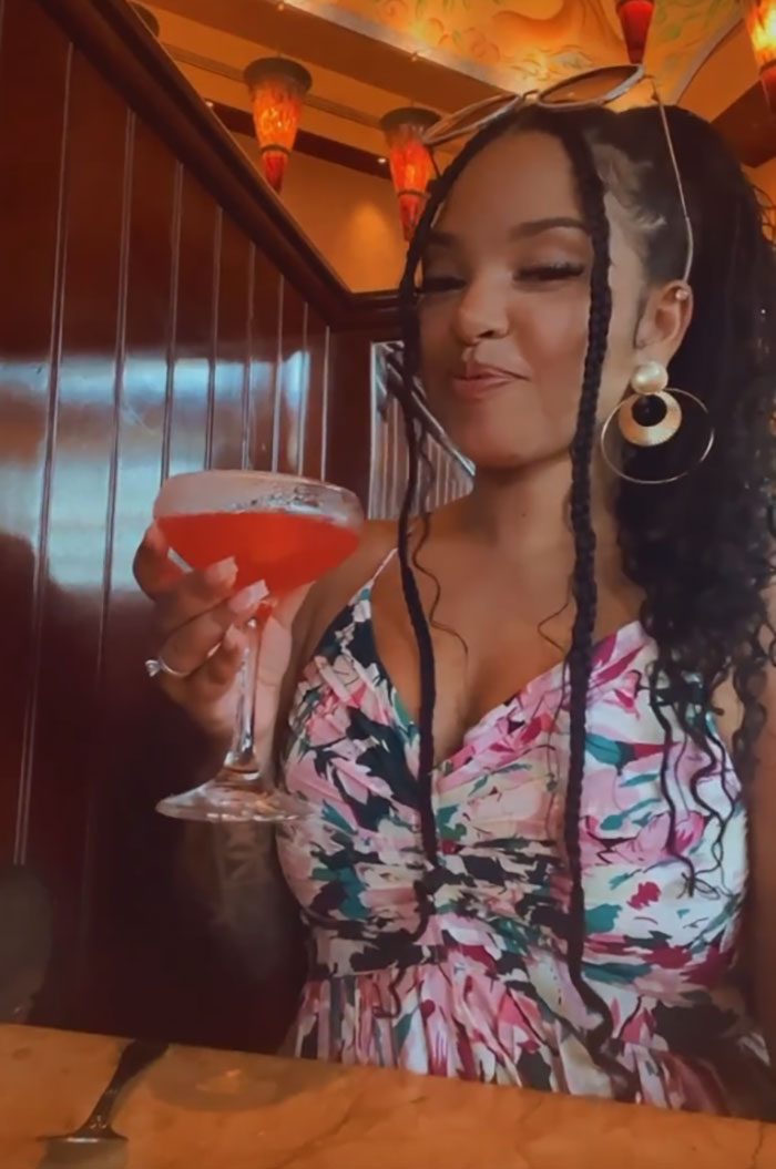 Woman in a floral dress enjoying a red cocktail, related to photographs with terrifying backstories.