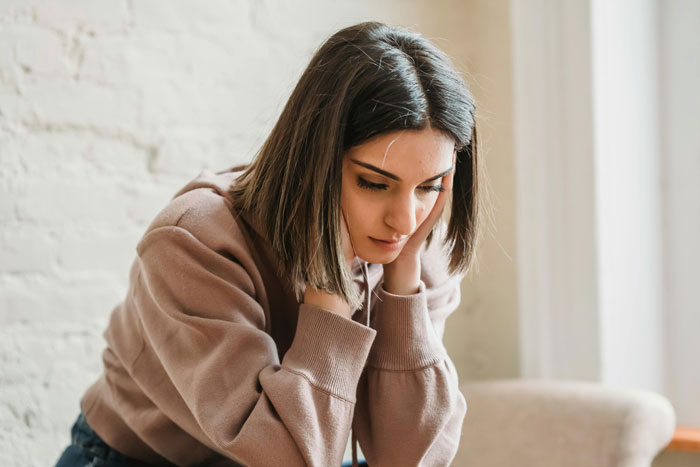 A woman in a casual sweater appears deep in thought, contemplating a booked holiday vacation.