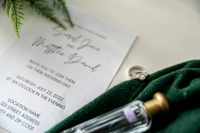 Wedding invitation with an engagement ring and perfume, highlighting guest list concerns for a gay woman. Wedding invitation with an engagement ring and perfume, highlighting guest list concerns for a gay woman.