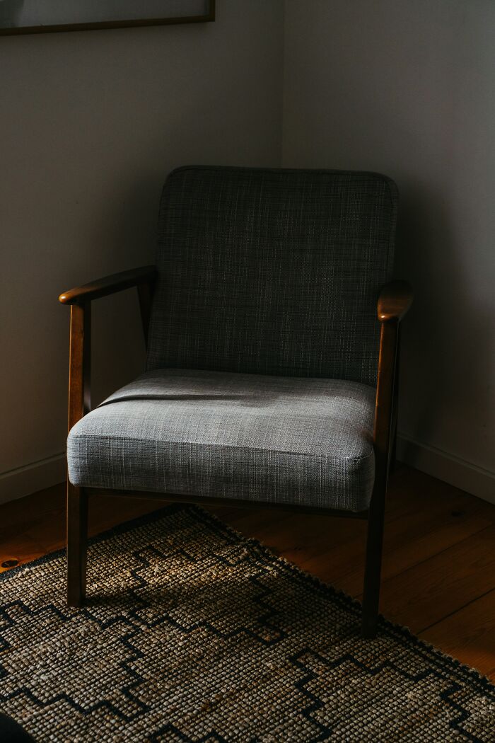 Cozy mid-century chair in a dimly lit room, showcasing a trendy interior design setting.