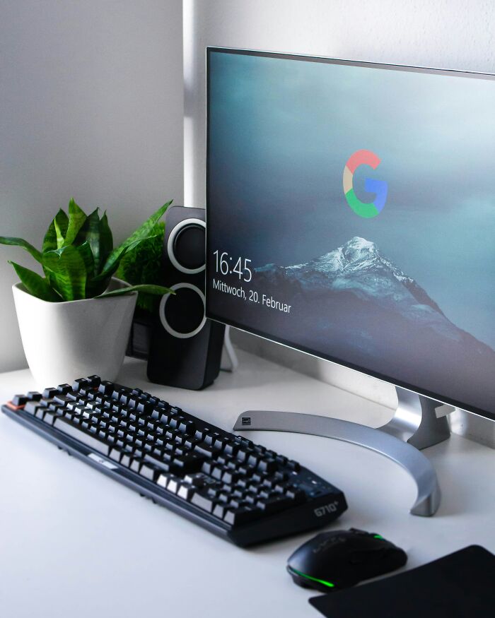 "Modern desktop with a monitor showing a Google login screen, keyboard, mouse, and plant in a tech setup."